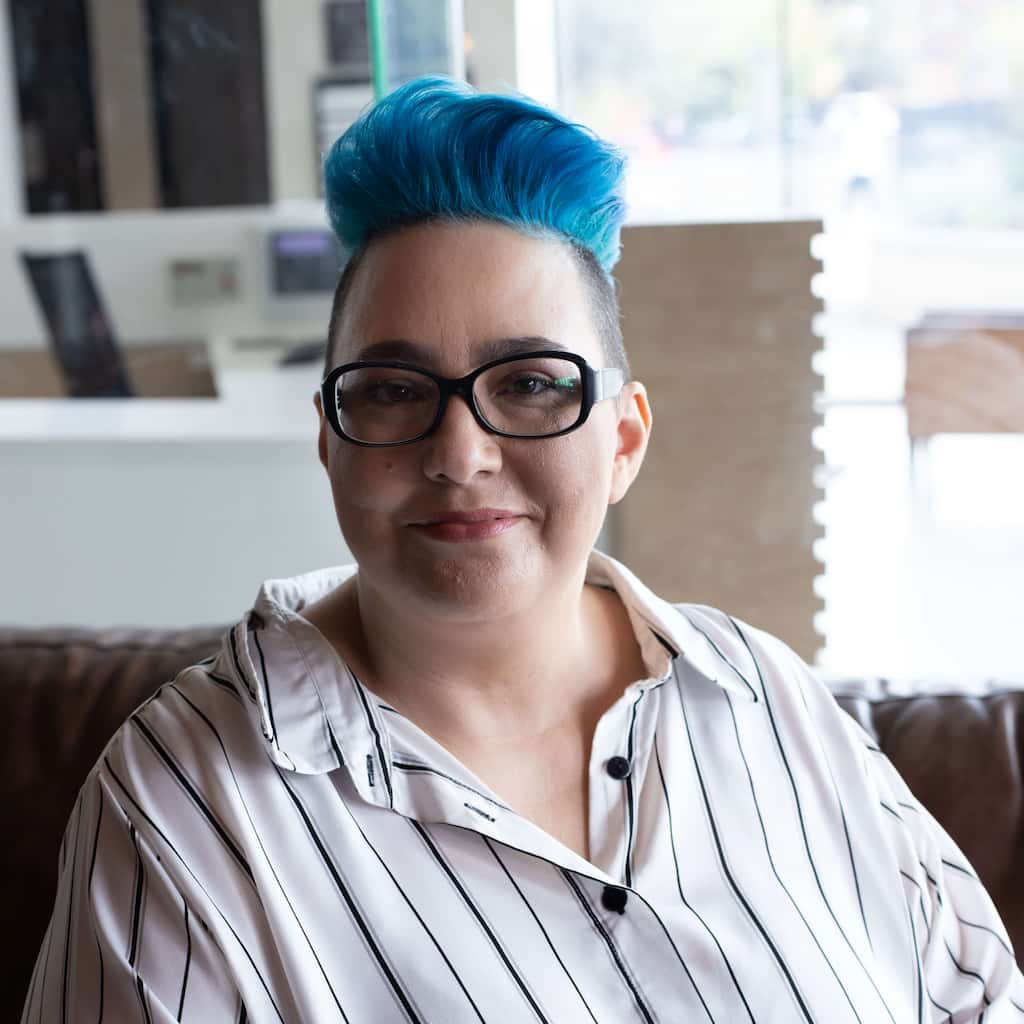 Portrait of blue-haired woman with glasses.