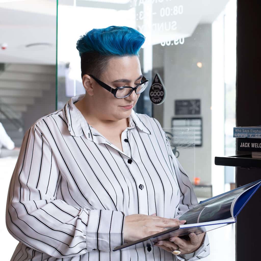Woman with wearing glasses reading book while standing.